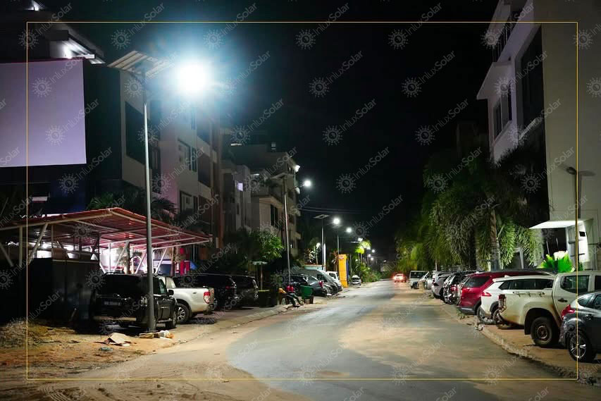 Night street scene with solar lighting over parked cars and roadside buildings