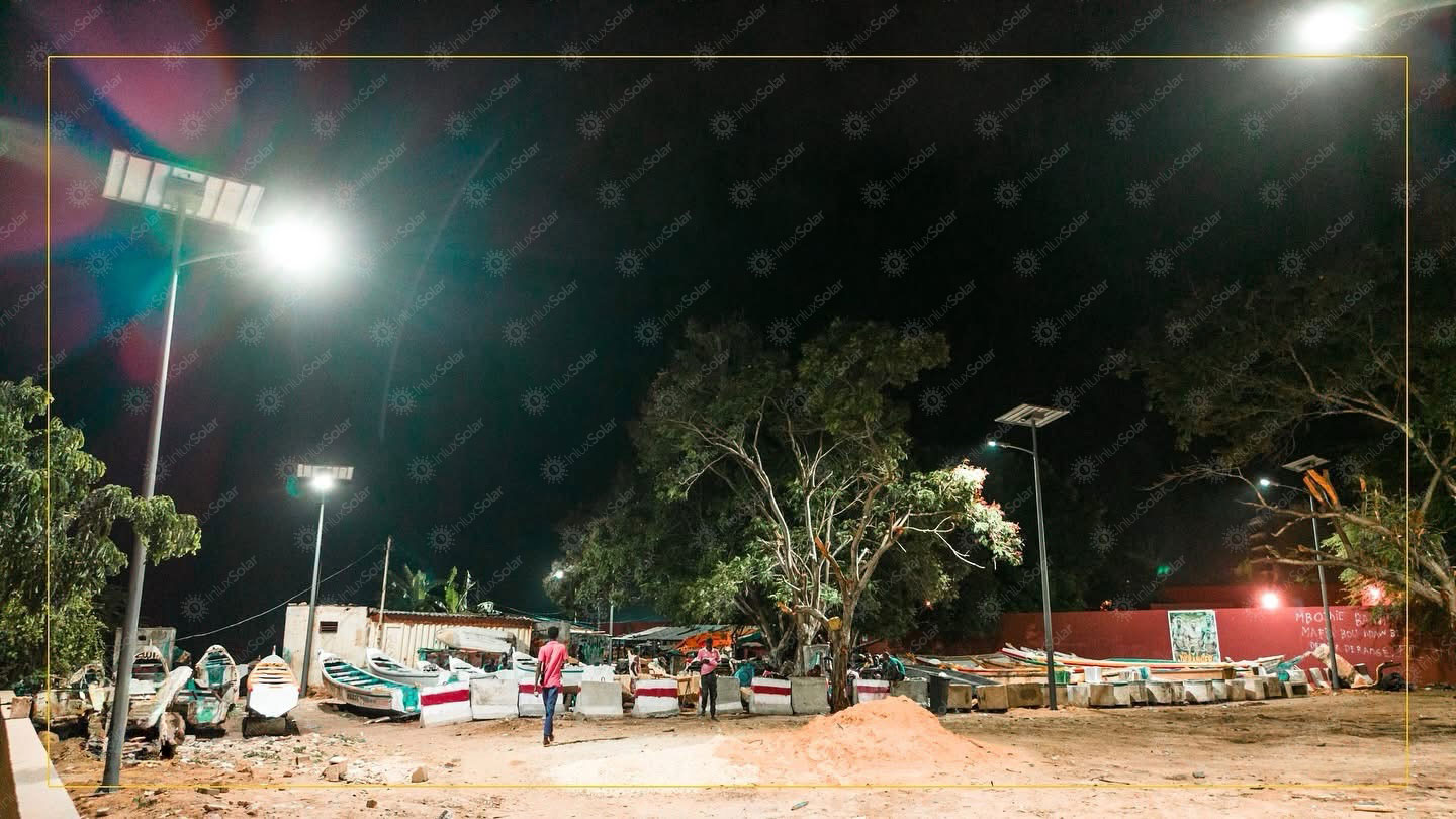 Community yard at night lit by solar street lights near trees and parked cars