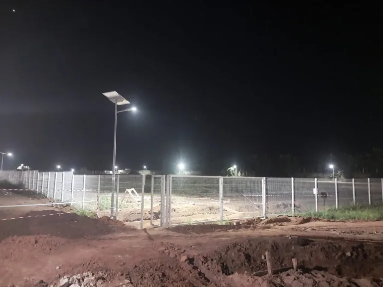Night view of a split type solar street light along a fenced industrial-zone site