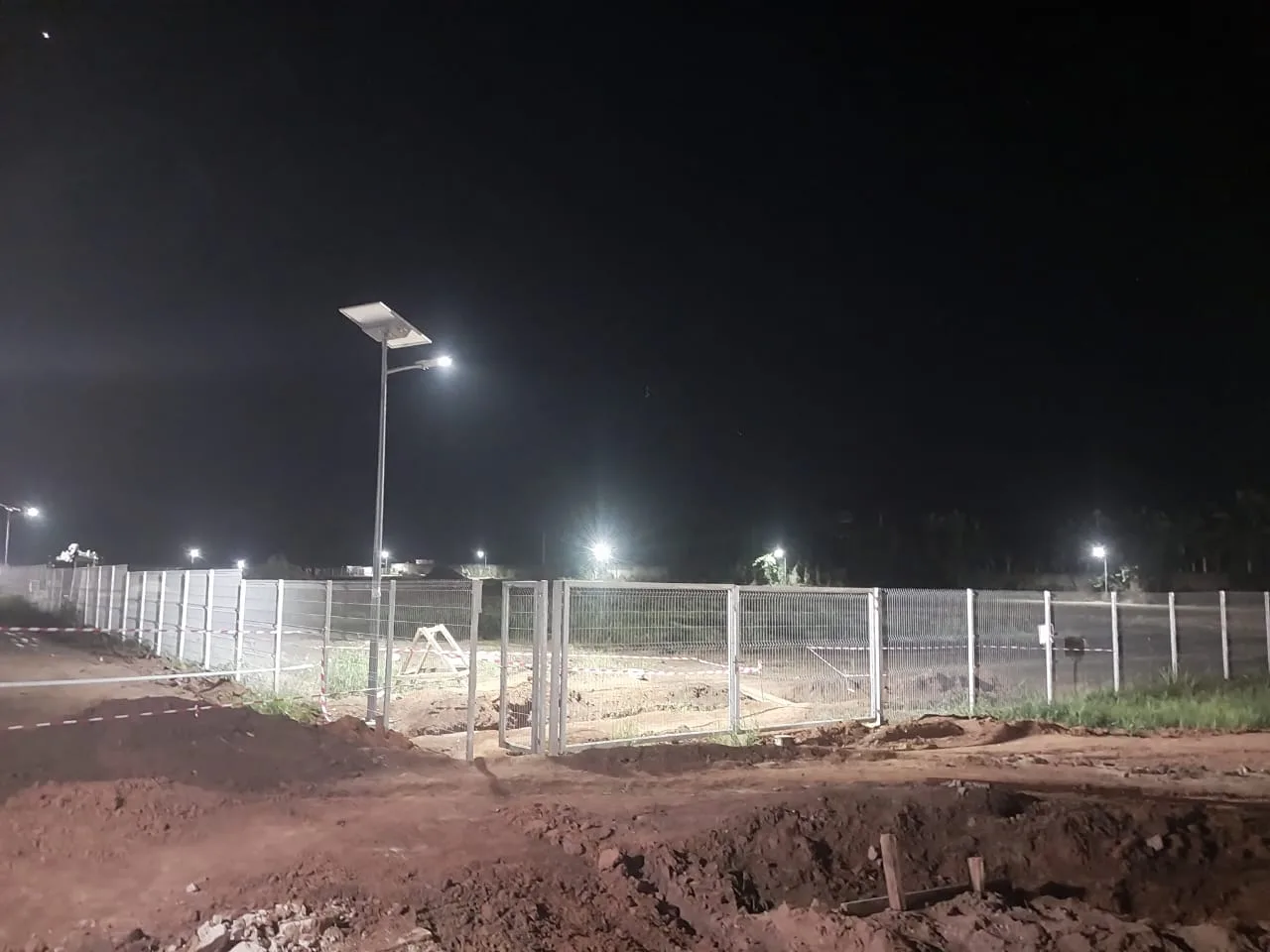 Night view of a split type solar street light along a fenced industrial-zone site