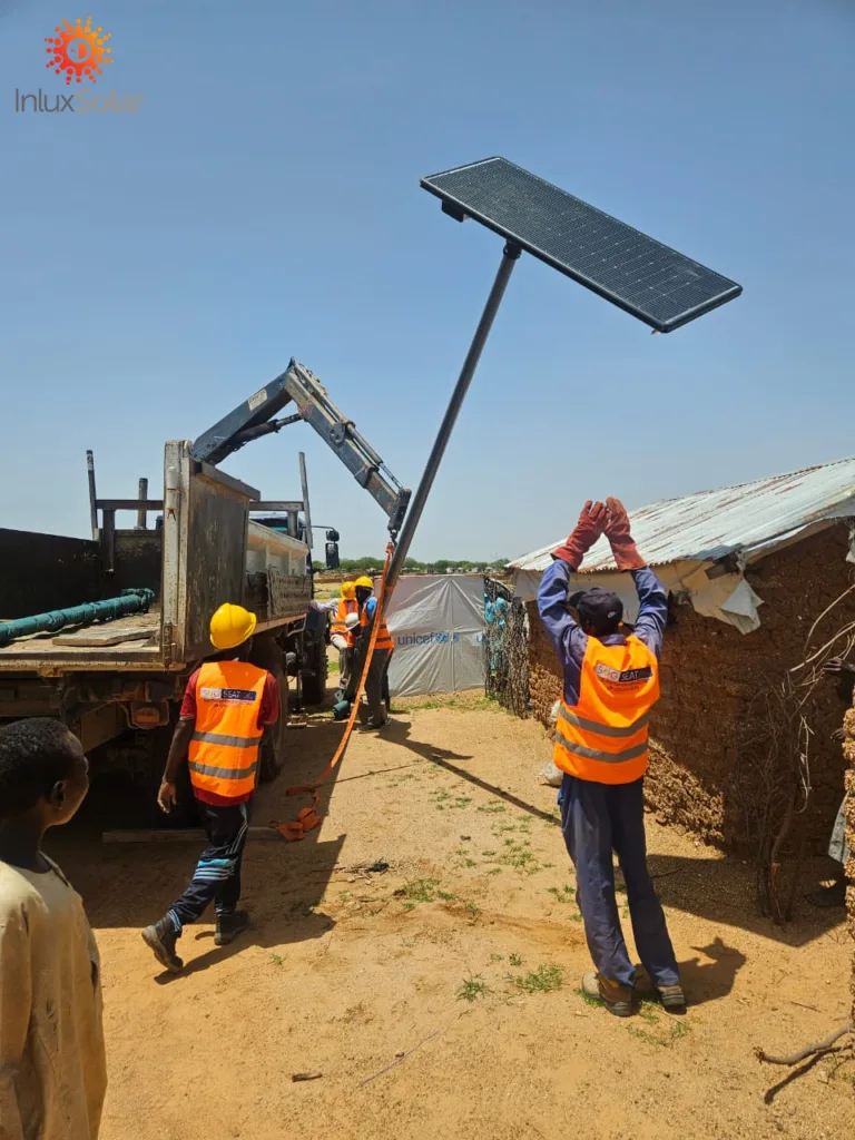 Local crew raising an AIO6 solar street light assembly at a rural site in Abéché, Chad