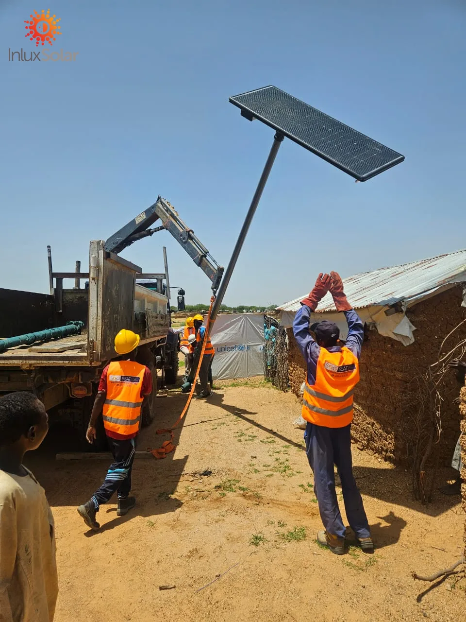 Local crew raising an AIO6 solar street light assembly at a rural site in Abéché, Chad