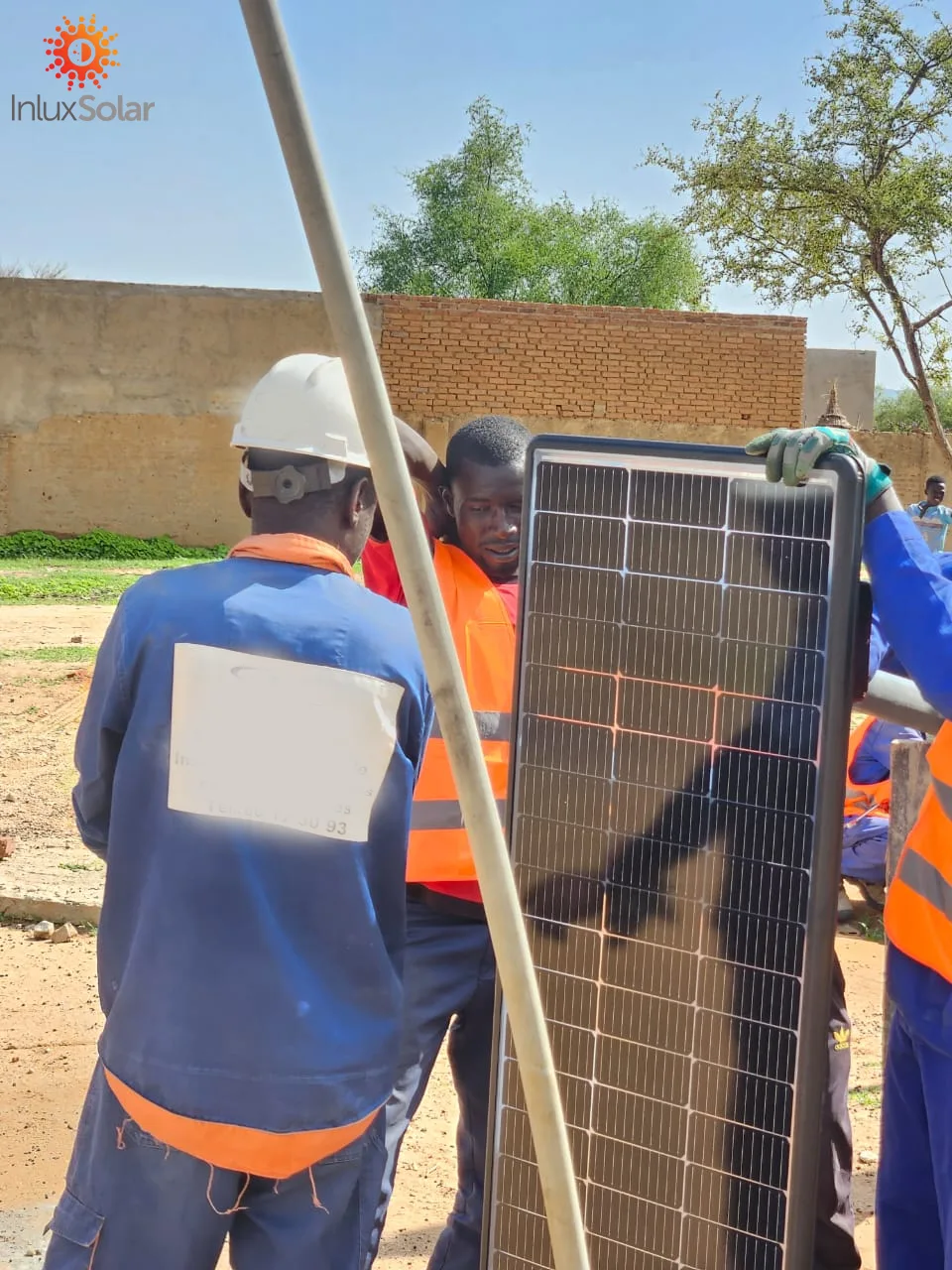 Close view of workers handling the solar panel and lighting assembly during installation